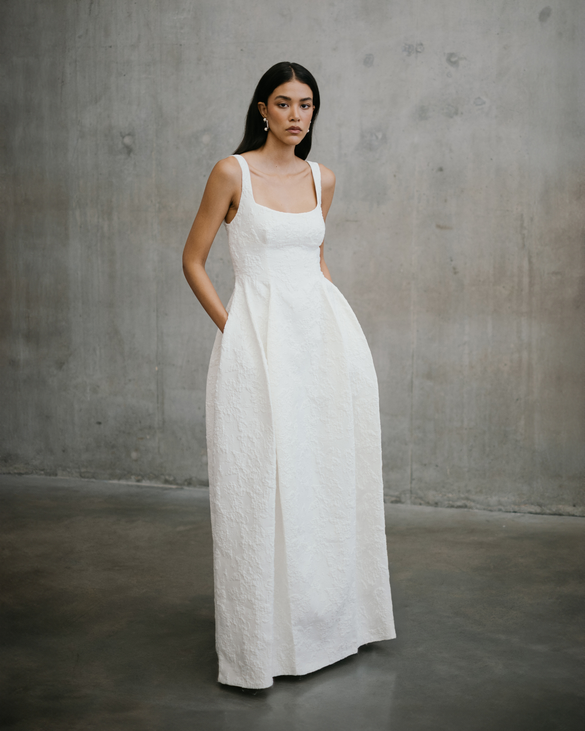 Full length portrait of the Unbridled Studio Thora gown featuring a pleated A-line skirt and relaxed pocket detail.