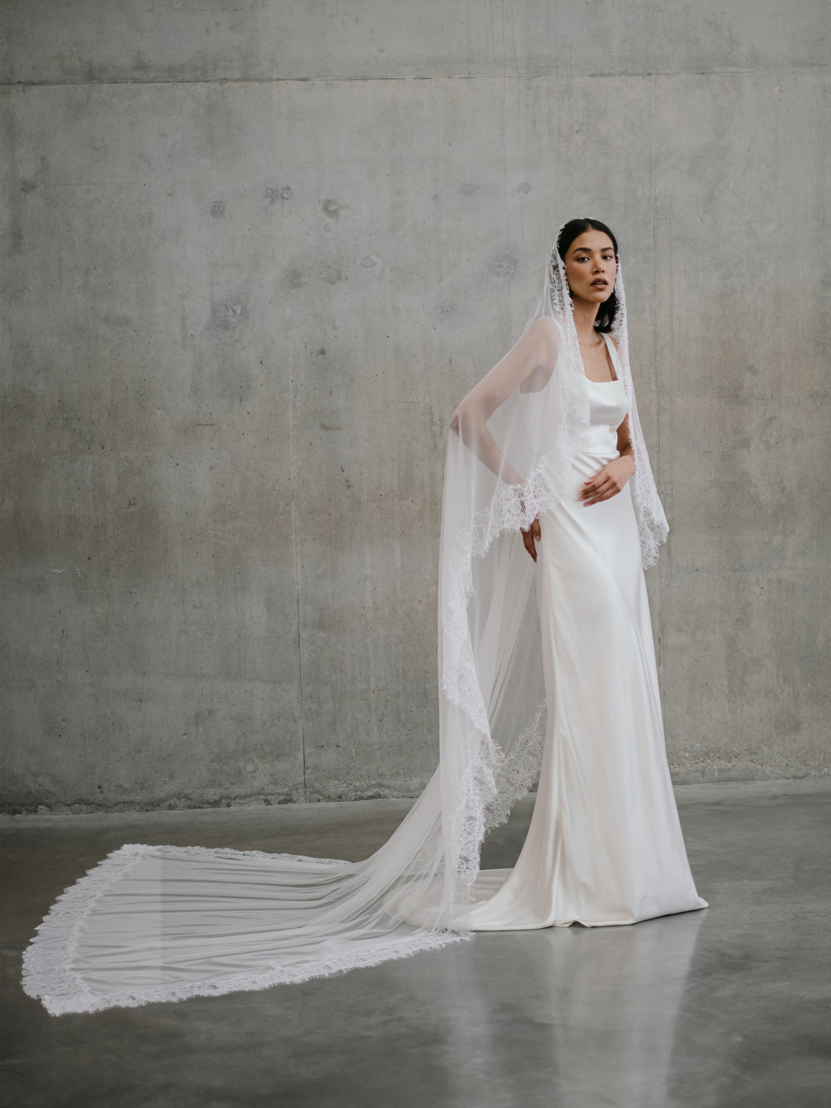 Full-length view of the Clara silk gown paired with a long cathedral-length lace-edged veil extending behind.