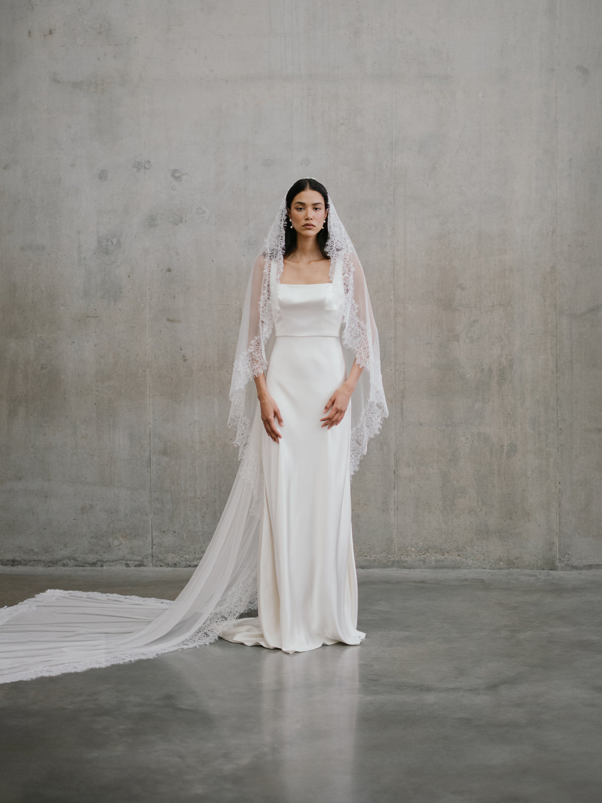 Full-length front portrait of the Unbridled Studio Clara gown styled with a dramatic lace veil.