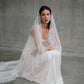 Seated portrait of model wearing the silk Clara wedding dress and lace-trimmed mantilla veil.