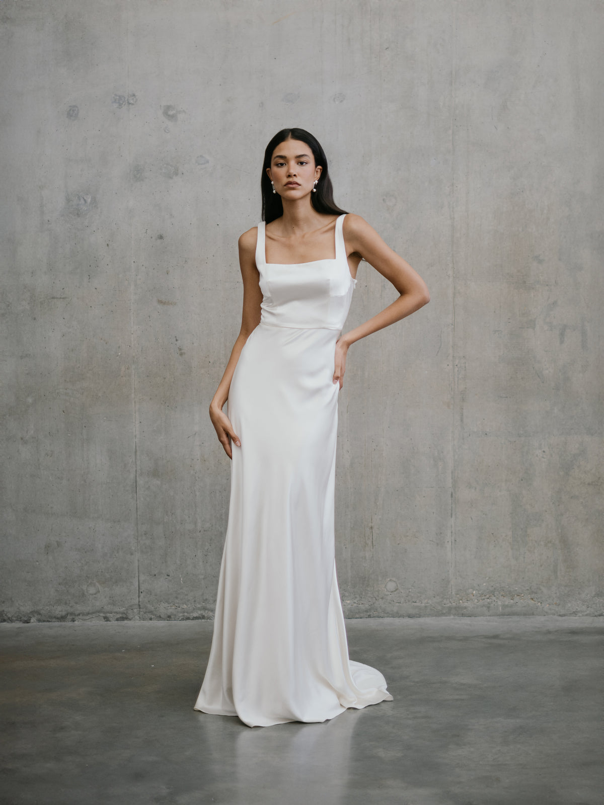 Standing full-length pose showing the minimalist silk silhouette and soft drape of the Clara wedding dress by Unbridled Studio.