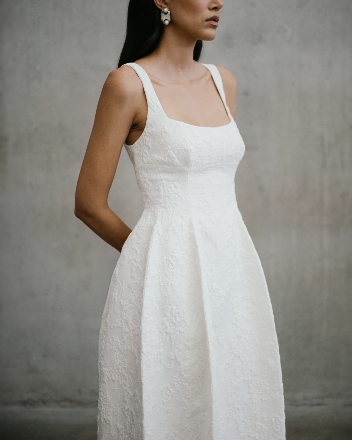 Detail view of the raised floral jacquard pattern and wide strap neckline on the Thora wedding dress.
