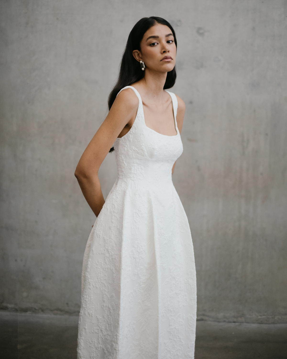 Three-quarter portrait of model wearing the Unbridled Studio Thora gown with wide shoulder straps and fitted waist.