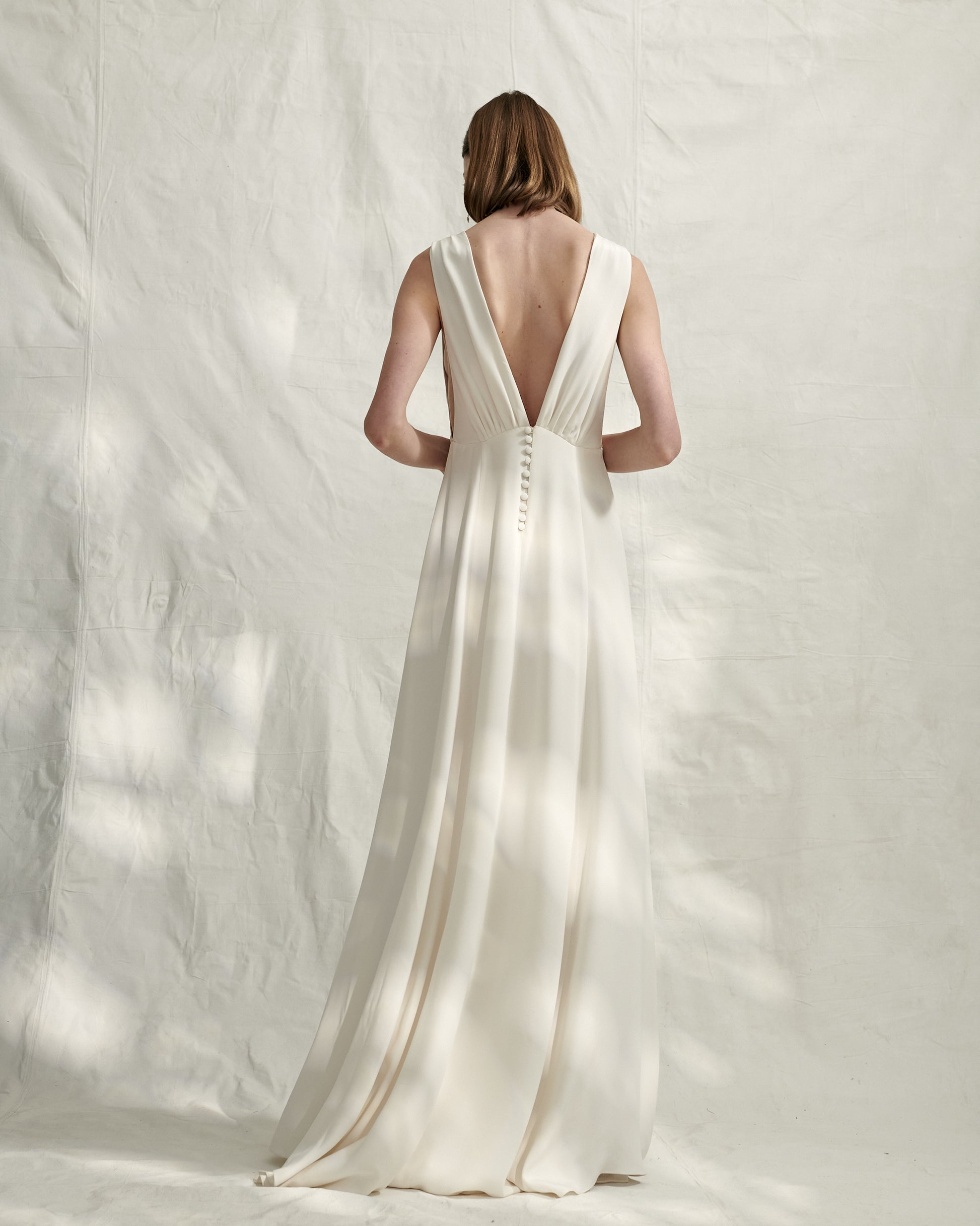 French designer silk crepe wedding gown with plunge neckline both front and back with optional belt.